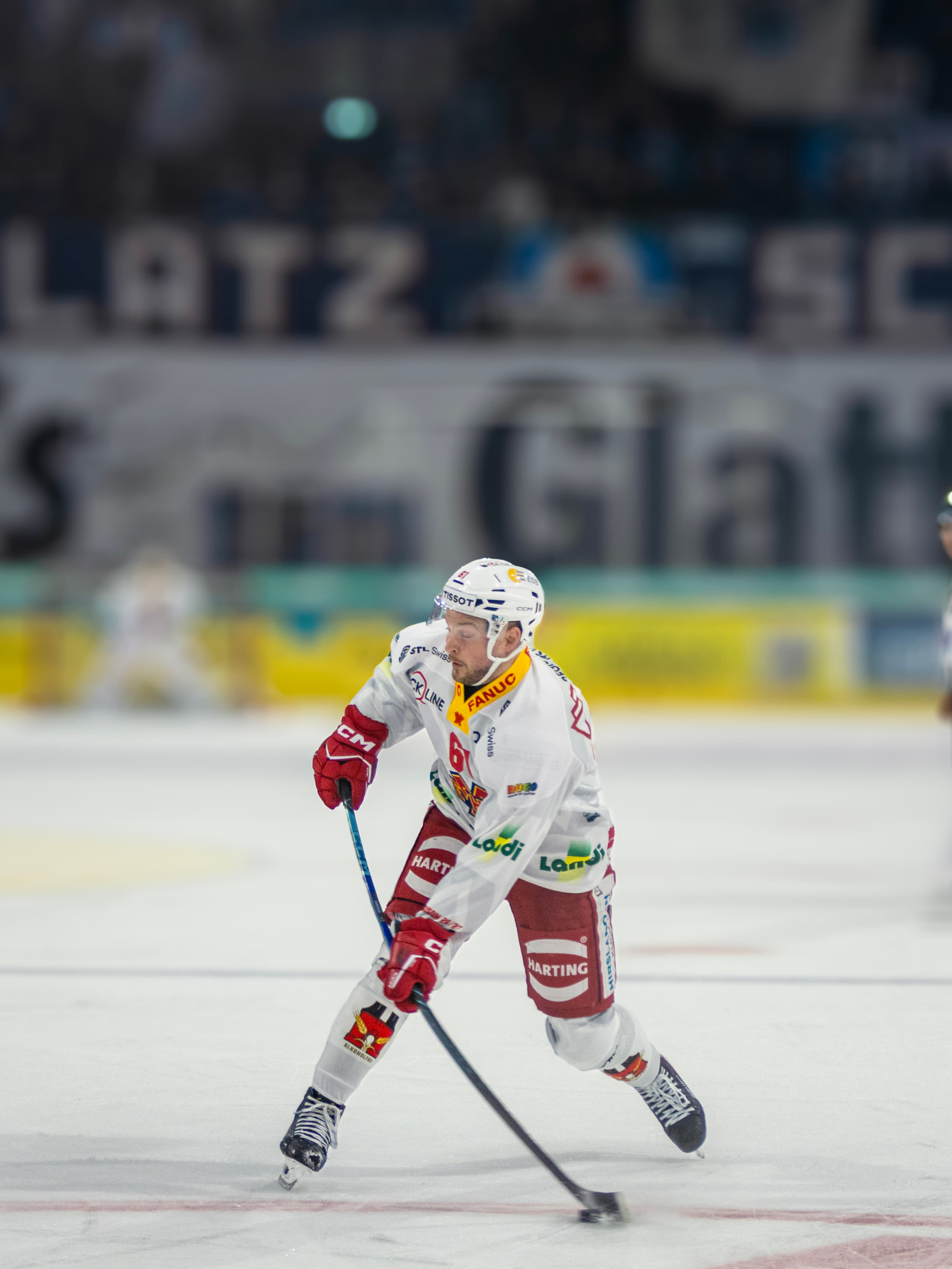 Biel-Spieler mit Puck vor der Fanchoreo an der Bande