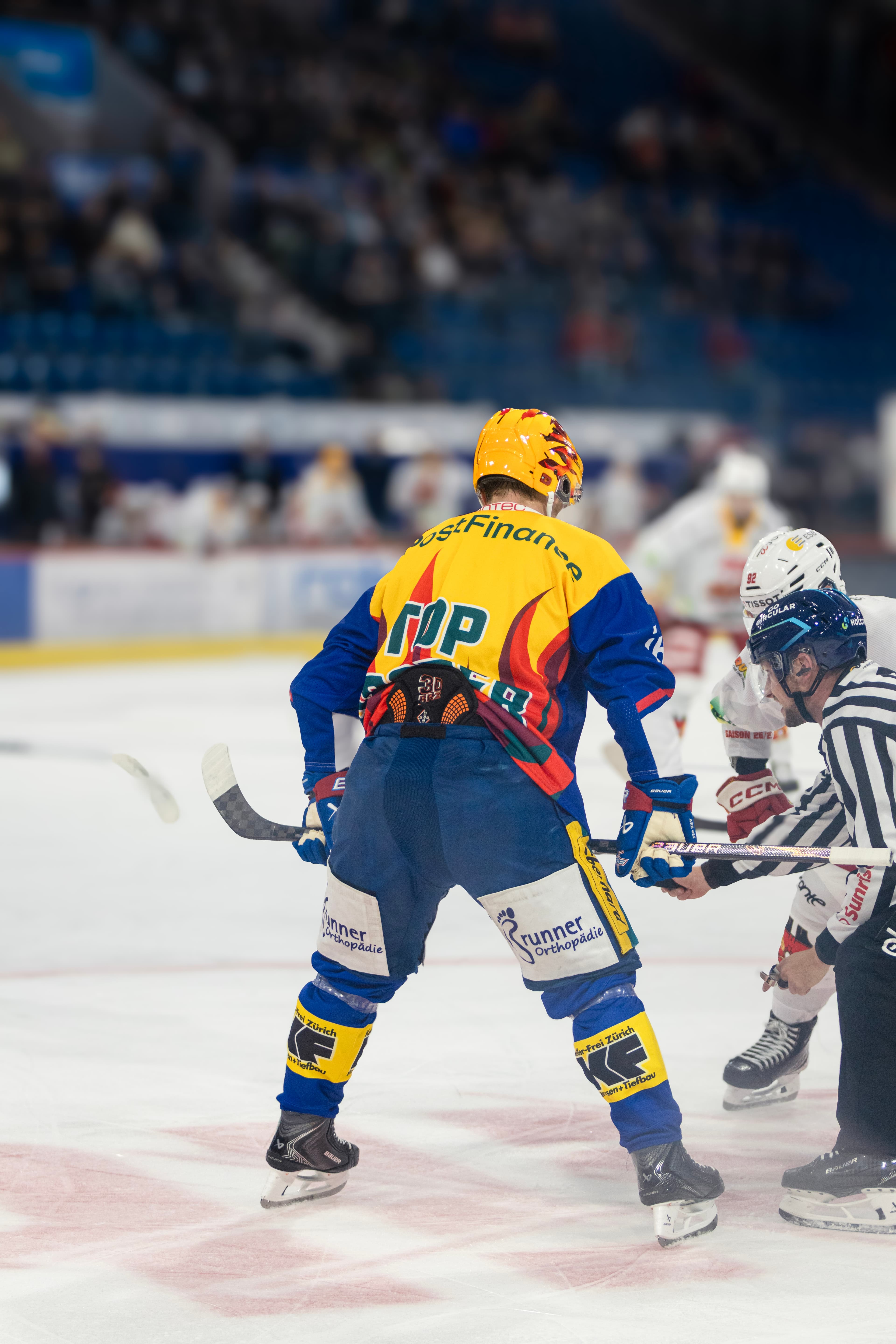 Bully mit Schiedsrichter, Kloten-Spieler mit PostFinance-Top-Scorer-Leibchen